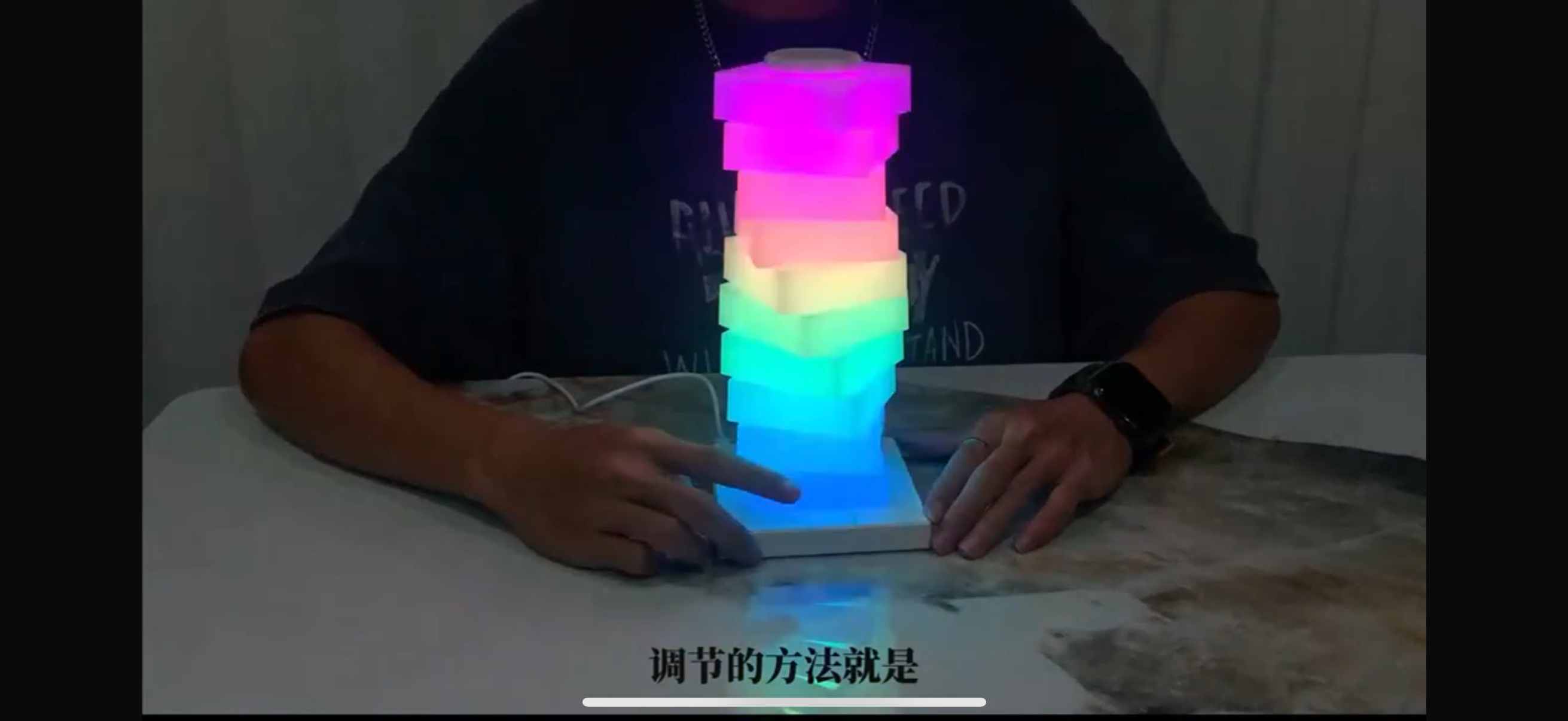 Person playing with a colorful LED tower on a table.