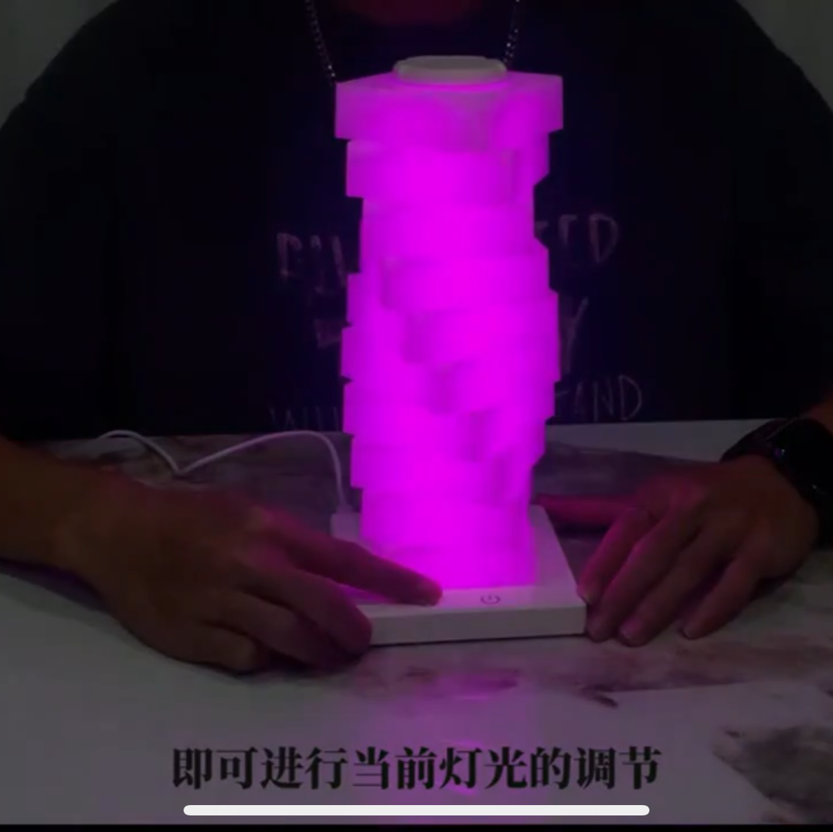 Person holding a glowing purple cylindrical object on a table