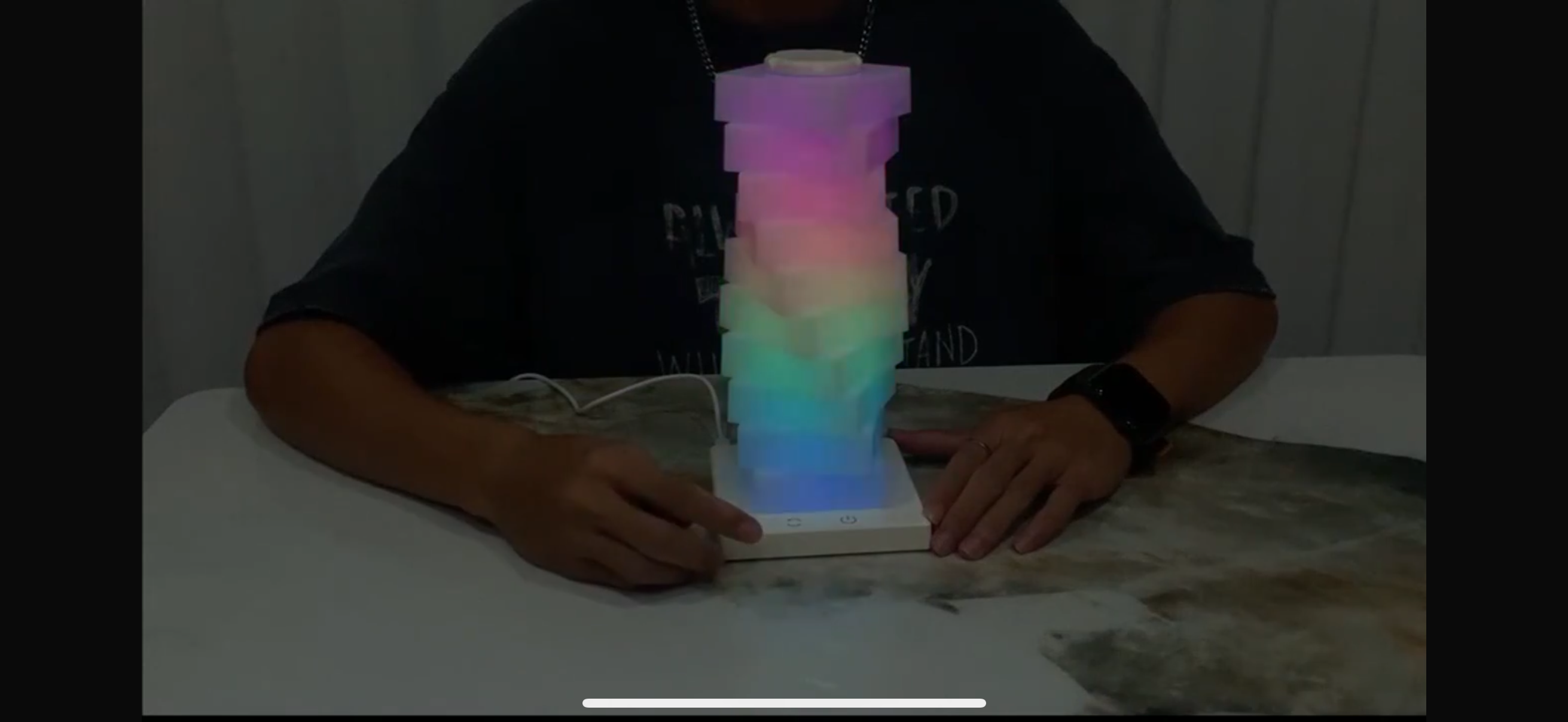 Person holding a colorful LED tower on a table
