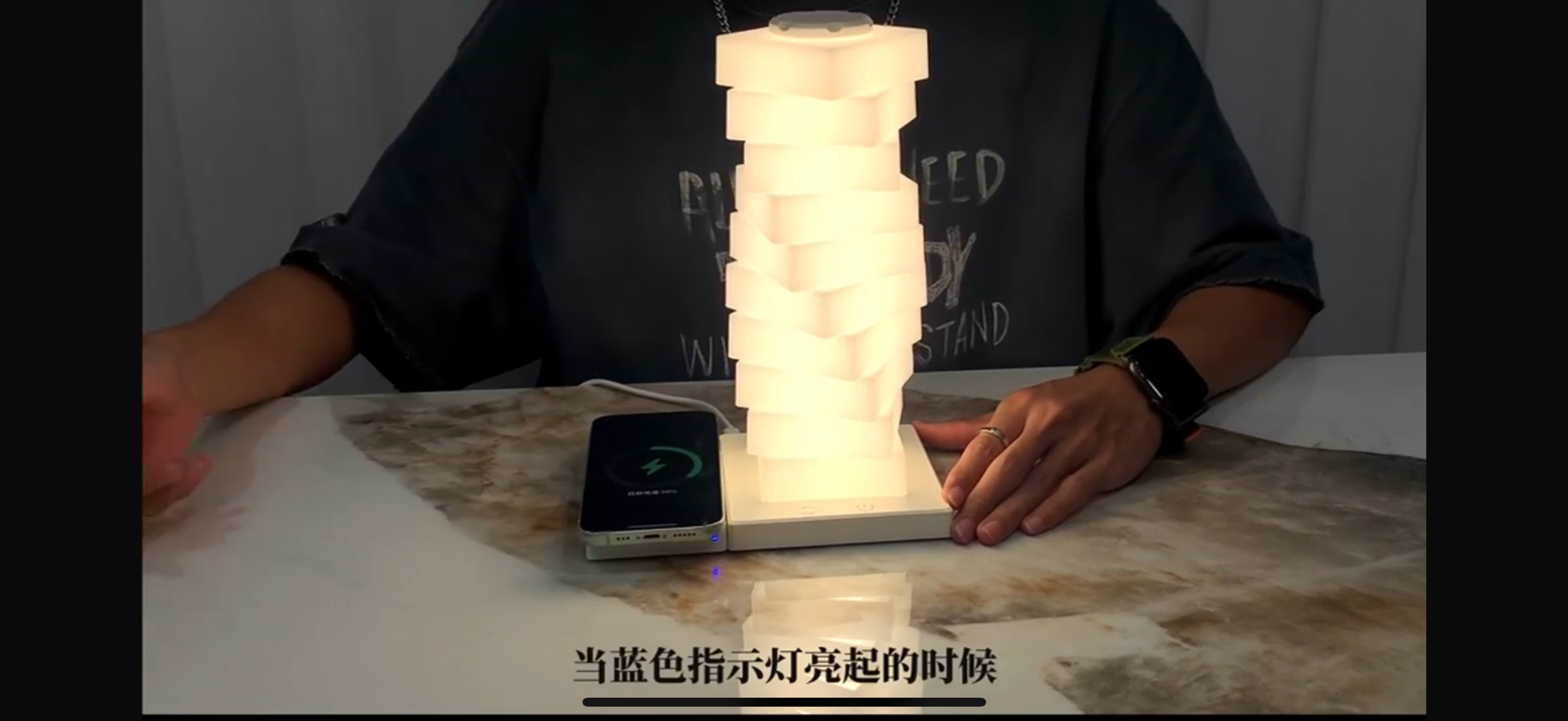 Person interacting with a glowing cylindrical light on a table