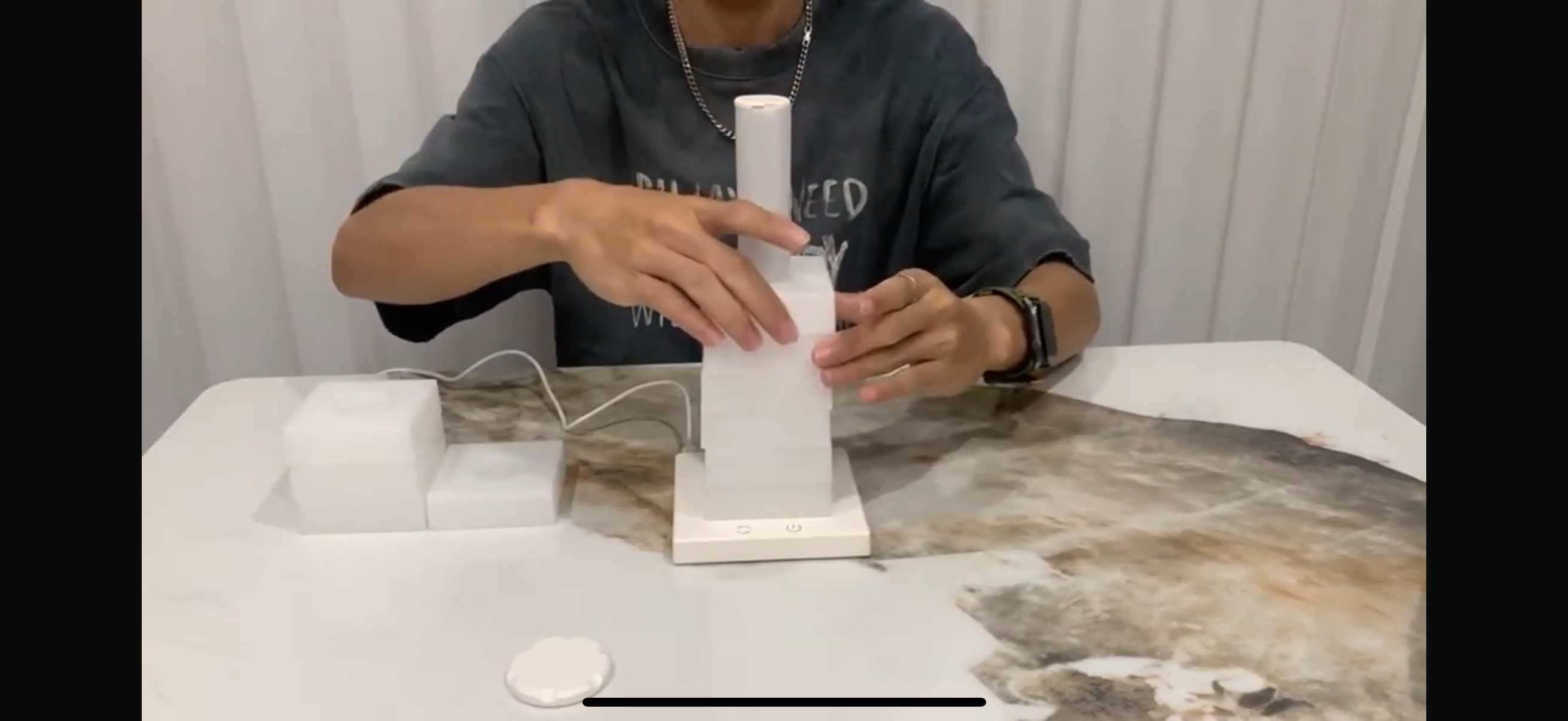 Person assembling a white electronic device on a table with a plain background